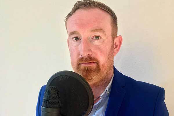 Austrian male voice-over talent with ginger hair and blue suit.