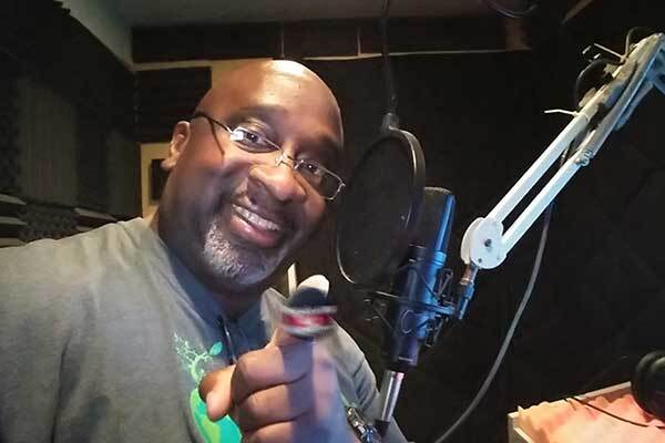 Happy male Jamaican voice-over talent points at camera.