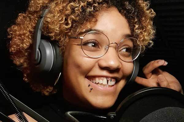 Black English female voice-over talent performs character script in studio.