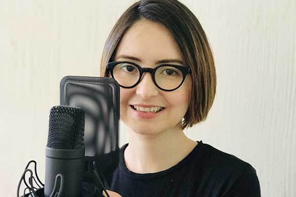 Female Chilean voice-over talent wearing glasses with condenser mic.